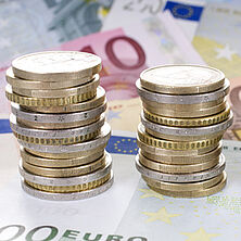 zu Türmen gestapelte Euromünzen, darunter Euroscheine