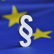 Paragrafenzeichen vor europäischer Fahne